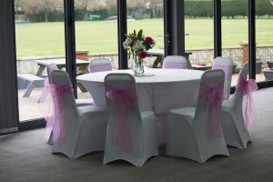 Weddings 1 room decorated with white tables, pink chair sashes and flower displays for wedding party
