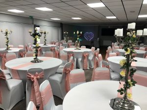 Weddings 2 room decorated with white tables, pink chair sashes and gothic flower displays for a wedding party